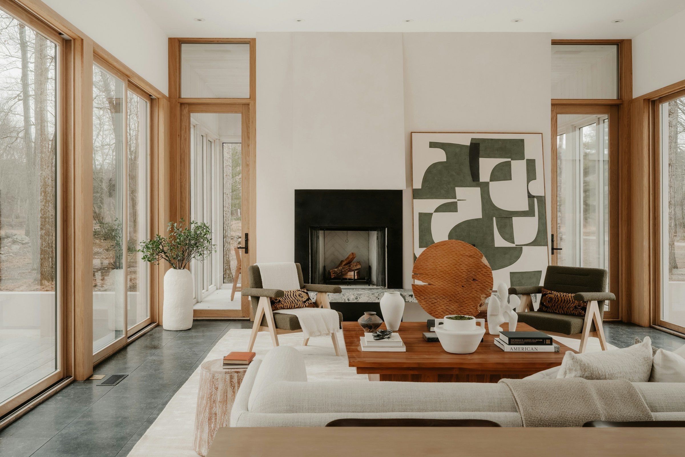 A living room with a fireplace, tall windows and warm wood