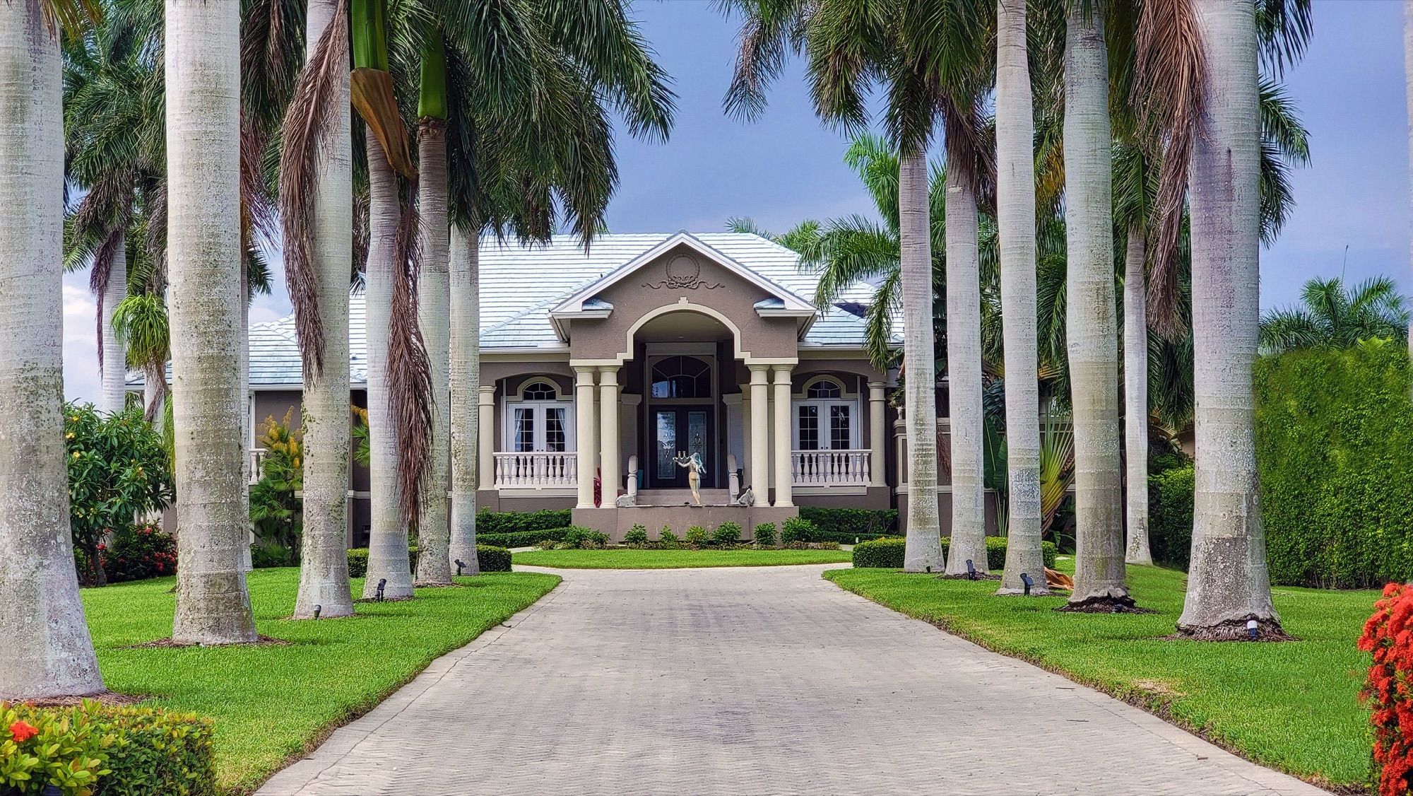 A stately house at the end of a palm-lined drive